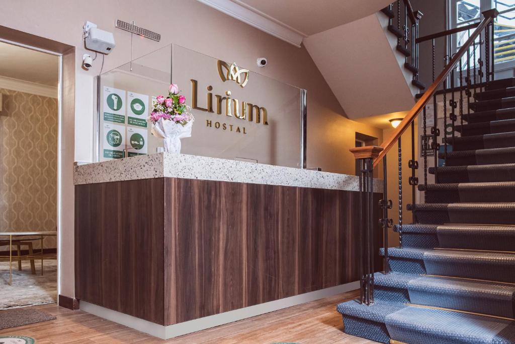 a lobby with a staircase and a counter with flowers at Hostal Lirium in Arequipa