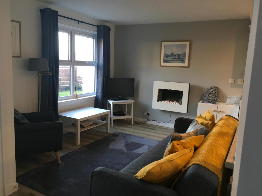 a living room with a couch and a fireplace at Cosy cottage with sea views close to local shops. in Lamlash