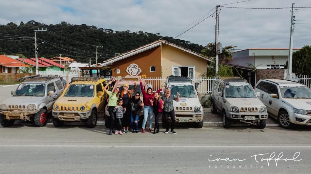 a group of people standing next to parked cars at Casa de Temporada Familiar in Urubici