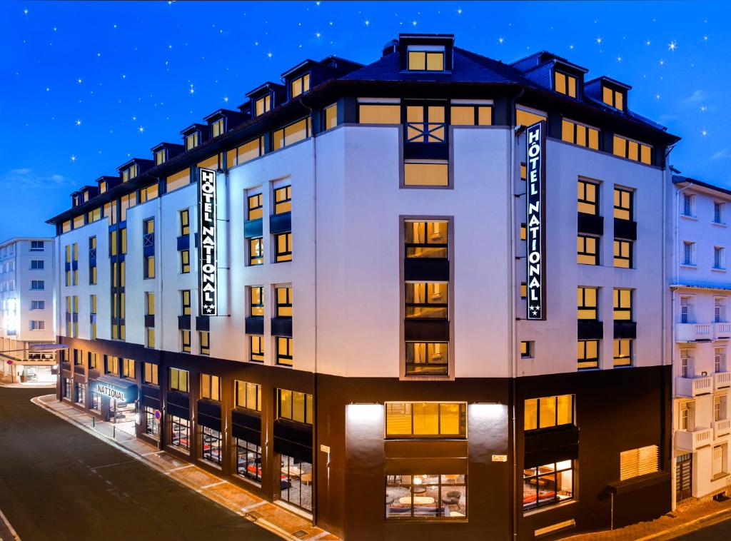 - un grand bâtiment blanc dans une rue de la ville la nuit dans l'établissement Hôtel National, à Lourdes