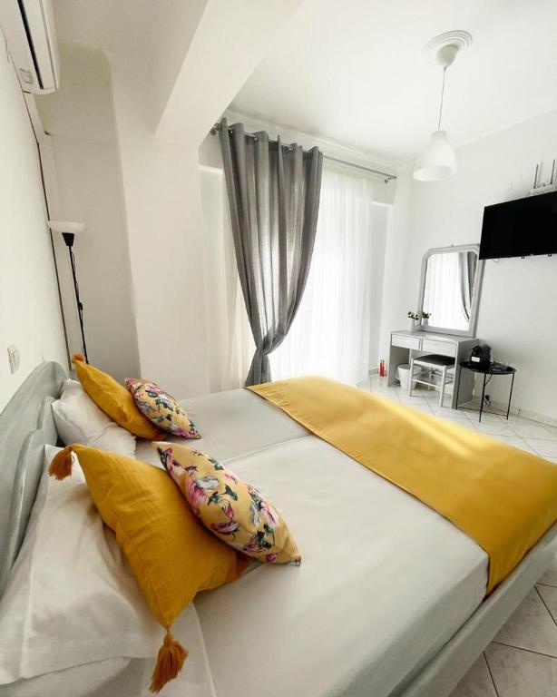1 dormitorio con 1 cama blanca grande con almohadas amarillas en ALEKA KOTSI ROOMS 2, en Igoumenitsa