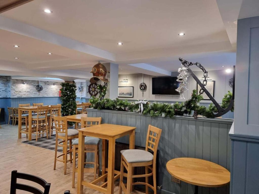 un bar con tavoli e sedie in legno in un ristorante di The Anchor Inn a Garelochhead