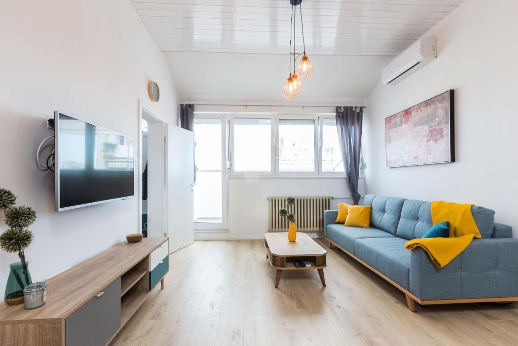 a living room with a blue couch and a tv at Kuki apartment with balcony in Zadar