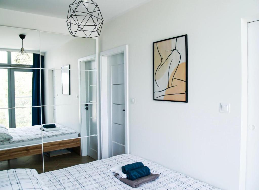 ein weißes Schlafzimmer mit einem Bett und einem Spiegel in der Unterkunft Nowoczesny Apartament z widokiem na jezioro in Charzykowy