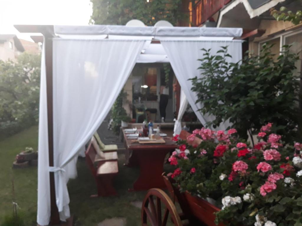pérgola blanca con mesa y flores en къща за гости Градина en Aheloy