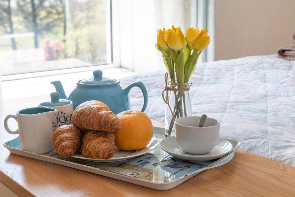 a tray with croissants and coffee cups and a tray of croissants at Arallt Holiday Cottage in Llithfaen