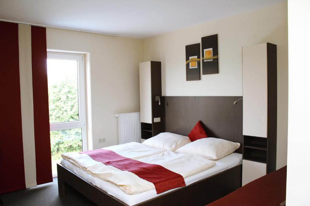 a bedroom with a bed with a red blanket on it at Arena Hotel in Henstedt-Ulzburg