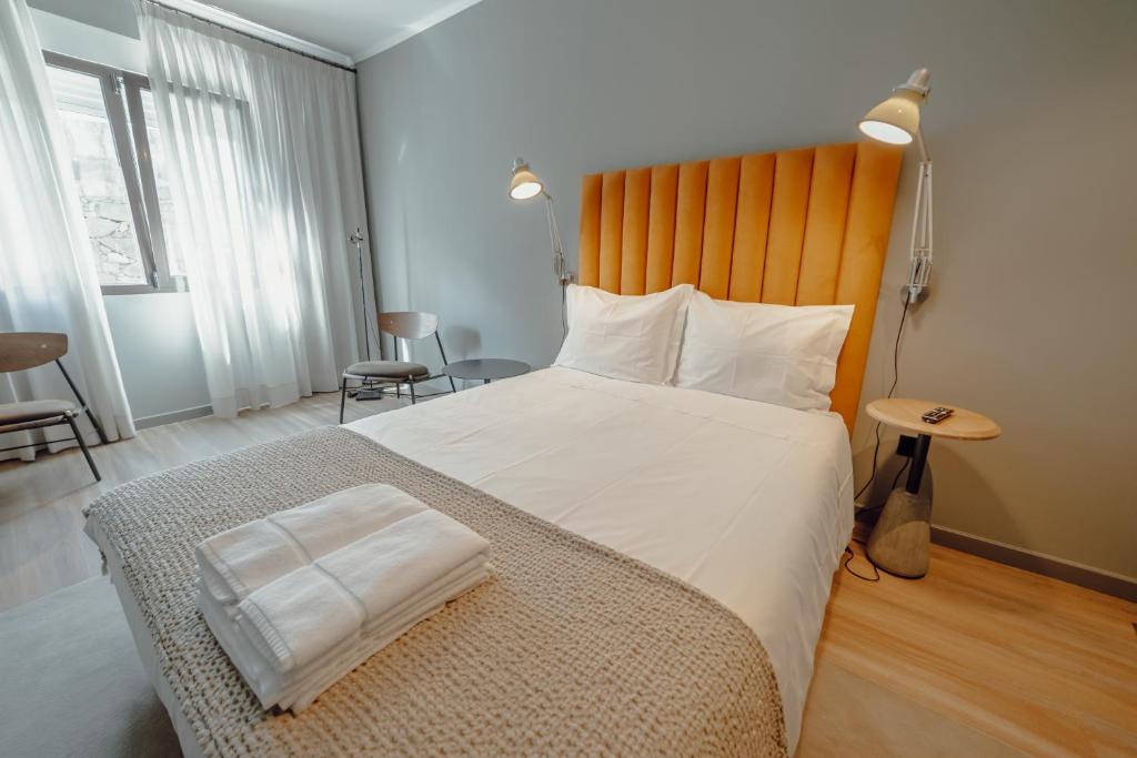 a bedroom with a large bed with a wooden headboard at River Eyes Suites in Vila Nova de Gaia