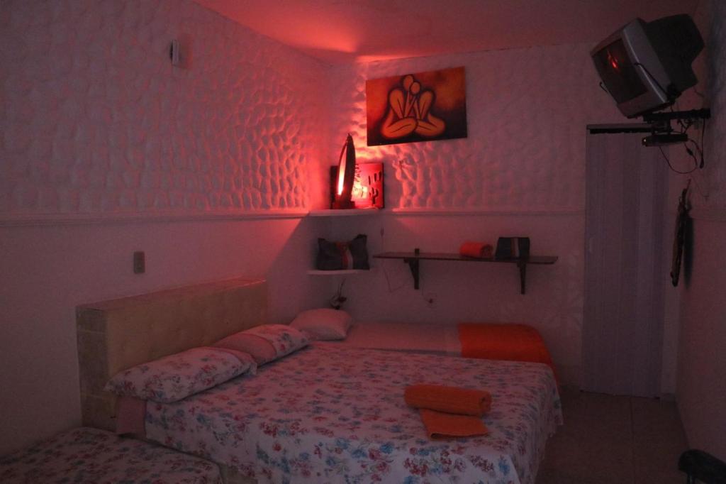 sypialnia z łóżkiem z różowym światłem w obiekcie Pousada Golfinho w mieście Galinhos