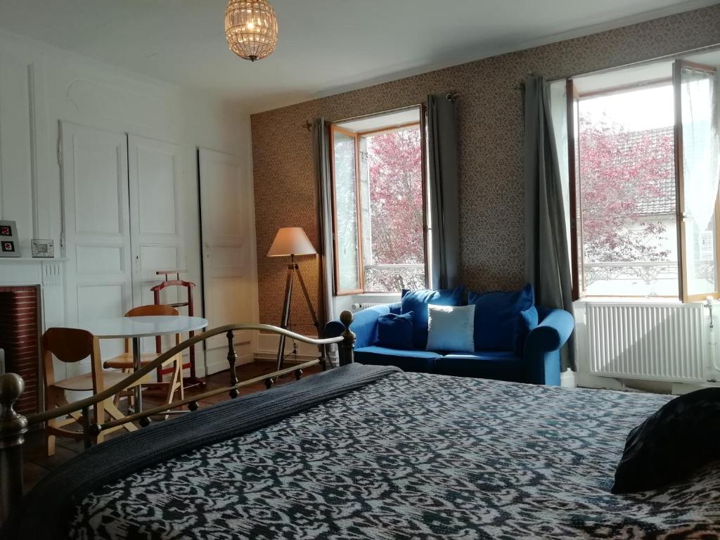 a bedroom with a bed and a blue couch at 3 Place des Arbres, Chambres D'Hôtes, Felletin in Felletin