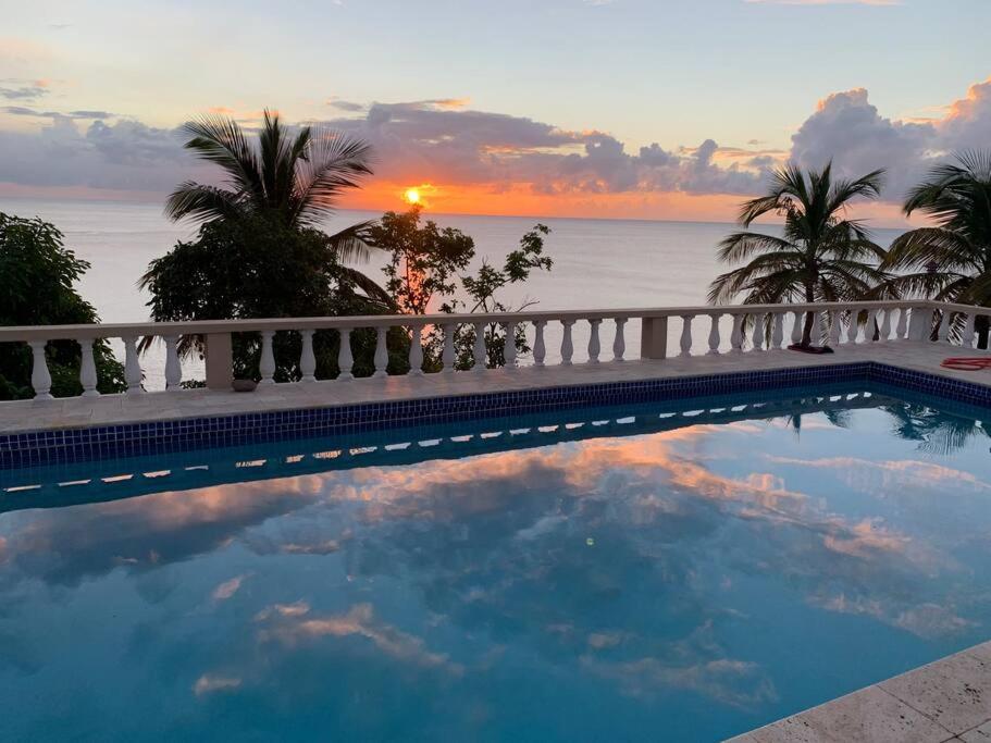 Oceanfront 3 bedrooms, 4beds, AC, WiFi, luxury villa في Woodlands: مسبح مع غروب الشمس في الخلفية
