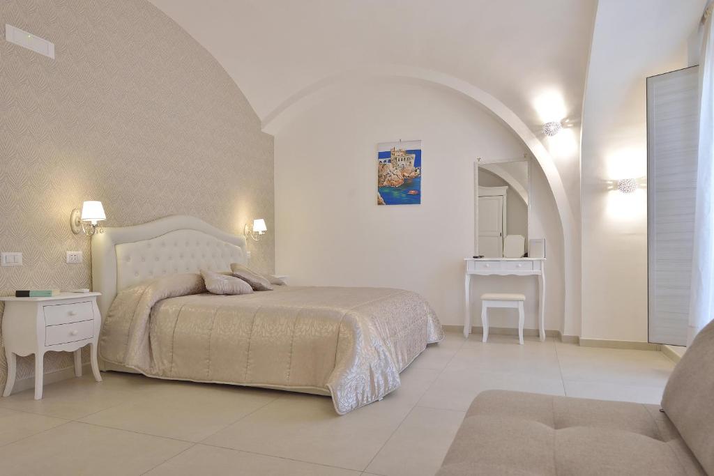 a white bedroom with a bed and a table at Sirena Apartment in Minori