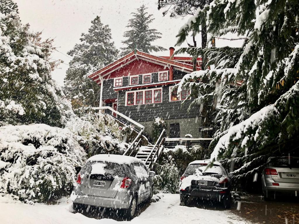 dos autos estacionados frente a una casa cubierta de nieve en La Miralejos en San Carlos de Bariloche