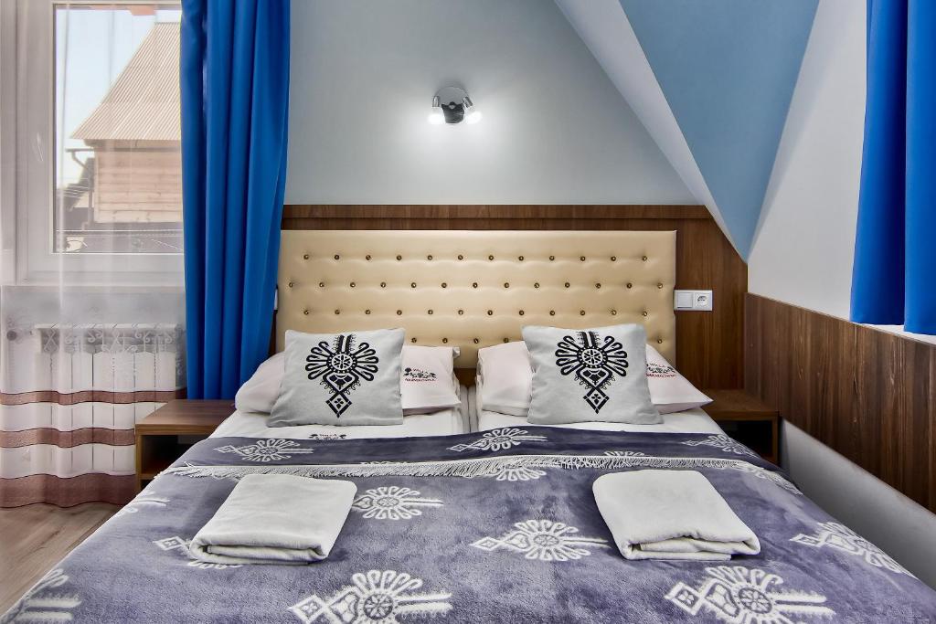 a bedroom with a bed with blue curtains at Willa Harnikówka in Białka Tatrzanska