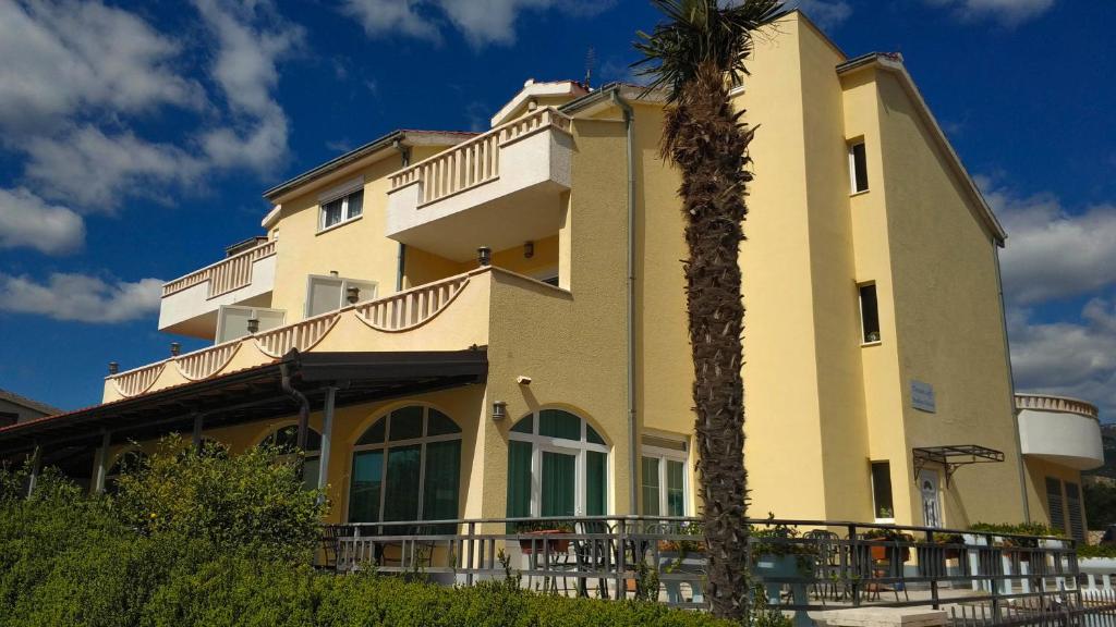 un edificio con una palma di fronte di Hotel Adria a Kaštela (Castelli)