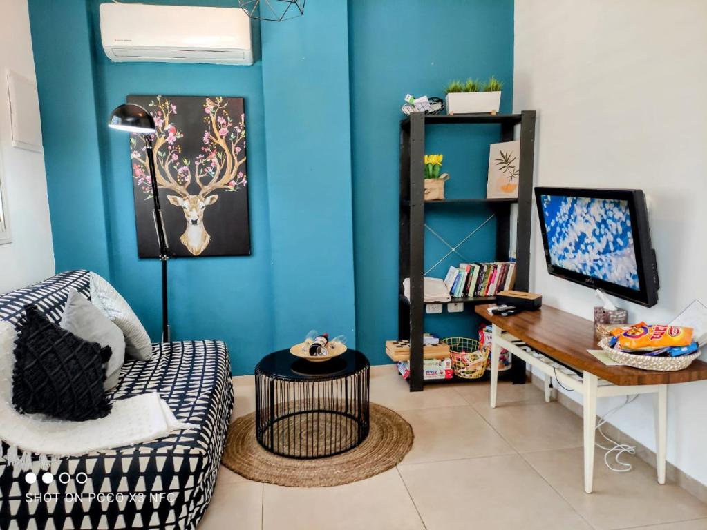 a living room with a blue wall and a desk at achzivacation Family Vacation Apt - 5mins to The Beach in Gesher HaZiw