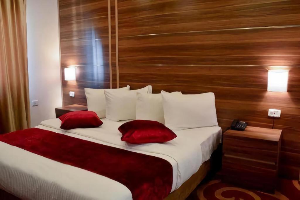 a bedroom with a large bed with two red pillows at Park Plaza Hotel in Amman
