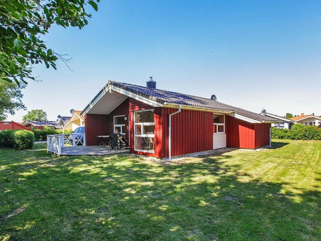 una casa rossa con un cortile davanti di Three-Bedroom Holiday home in Grömitz 7 a Grömitz