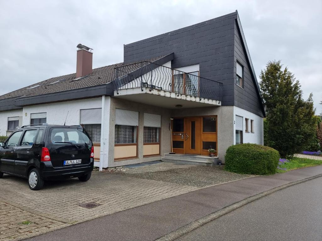 uma carrinha preta estacionada em frente a uma casa em Appartment Gude, Ulm- Stuttgart em Heroldstatt