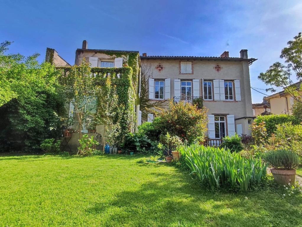 una vieja casa con hiedra al lado de un patio en La Prévôté en Moissac