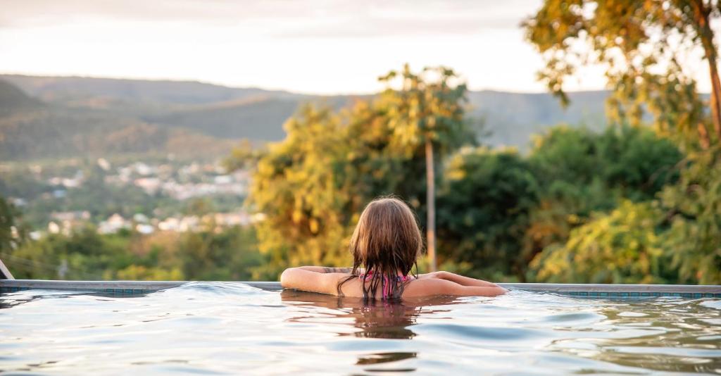 una mujer sentada en el agua en una piscina en Pousada Boutique Mirante d'Italia, en Pirenópolis