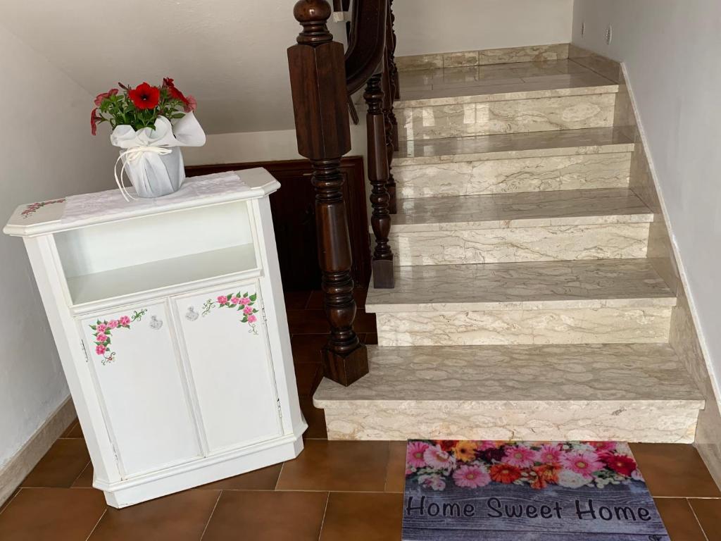 un armario blanco con flores al lado de una escalera en A casa di Bea sulla Francigena en San Miniato