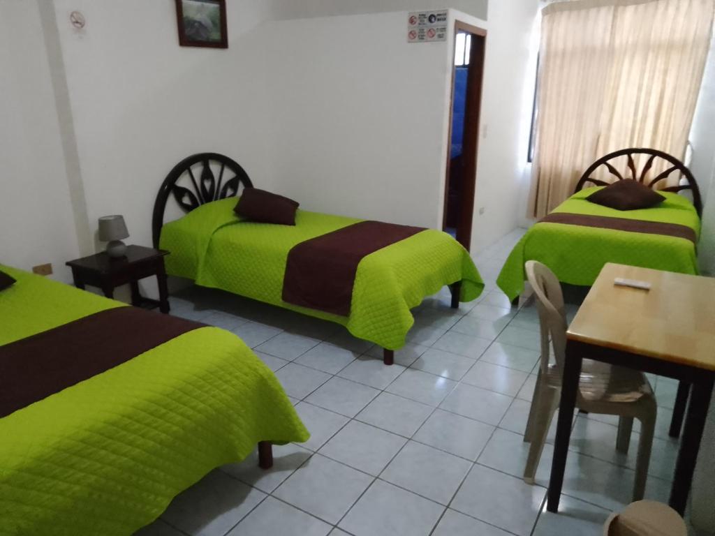 a room with two beds and a table and a table and chairs at Hotel Isla del descanso in Puerto Villamil