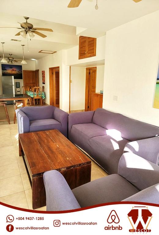 a living room with purple couches and a wooden table at Sunset Waves in Roatan