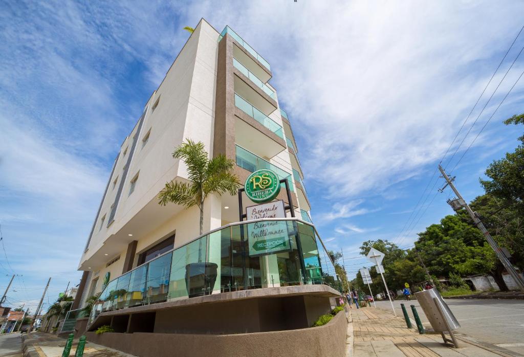 a building with a palm tree in front of it at Hotel Ribera Sinu in Montería