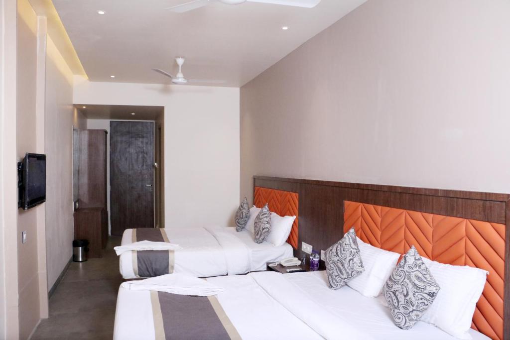 a hotel room with two beds and a television at Hotel Park Side in Vasai