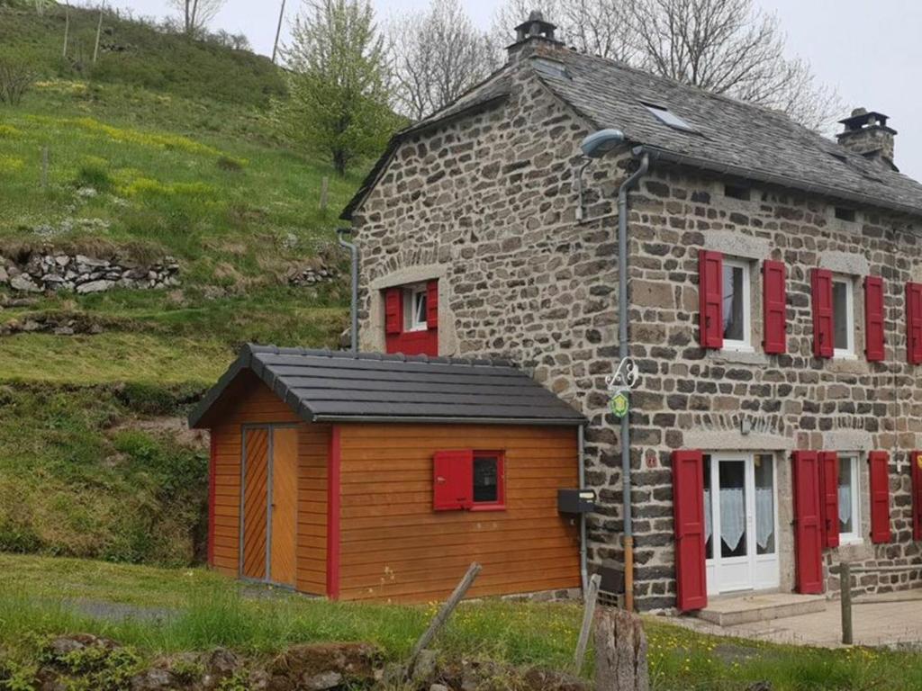 una pequeña casa de piedra con puertas y ventanas rojas en Gîte Les Estables, 4 pièces, 6 personnes - FR-1-582-143, en Les Estables