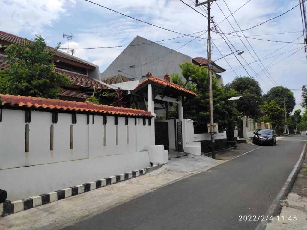 a street with a white wall and a car on the road at Kelana 2 Nice Homestay (5 Bed Rooms) Semarang in Semarang