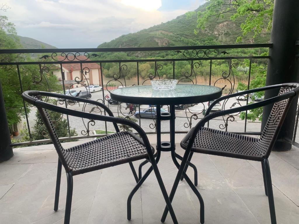 a glass table and two chairs on a balcony at La Home in Mtskheta