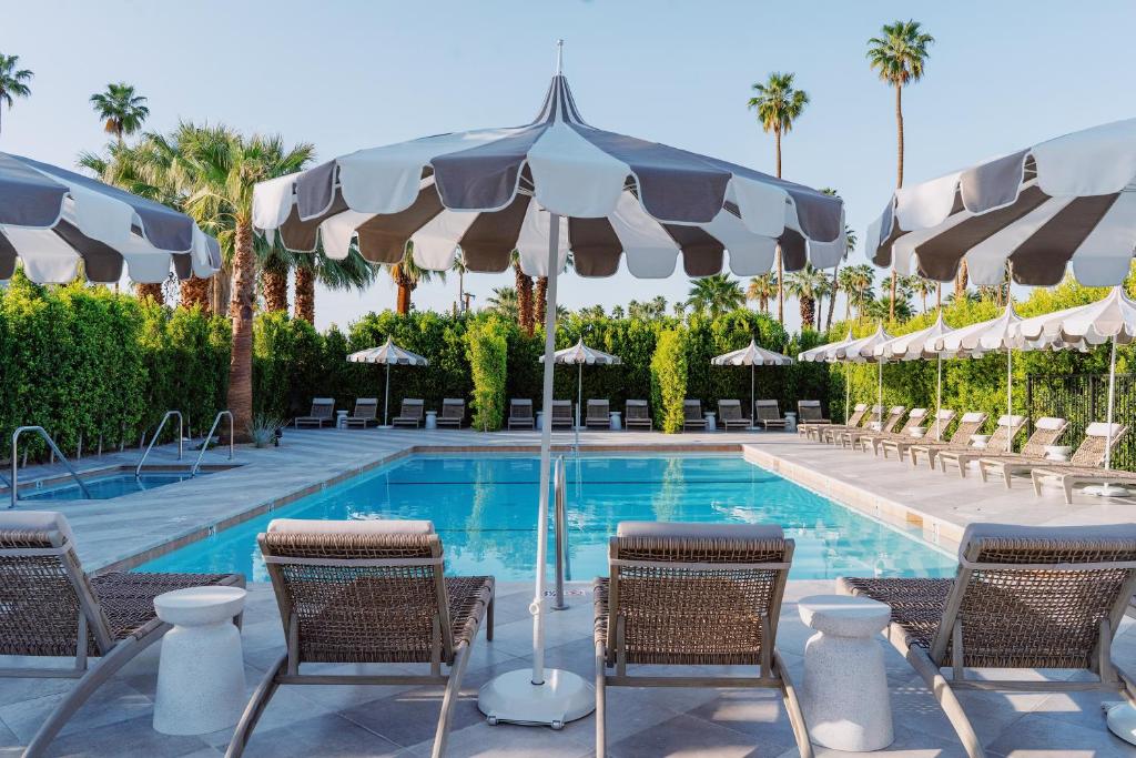 a swimming pool with chairs and umbrellas next to a resort at Azure Sky Hotel - Adults Only in Palm Springs