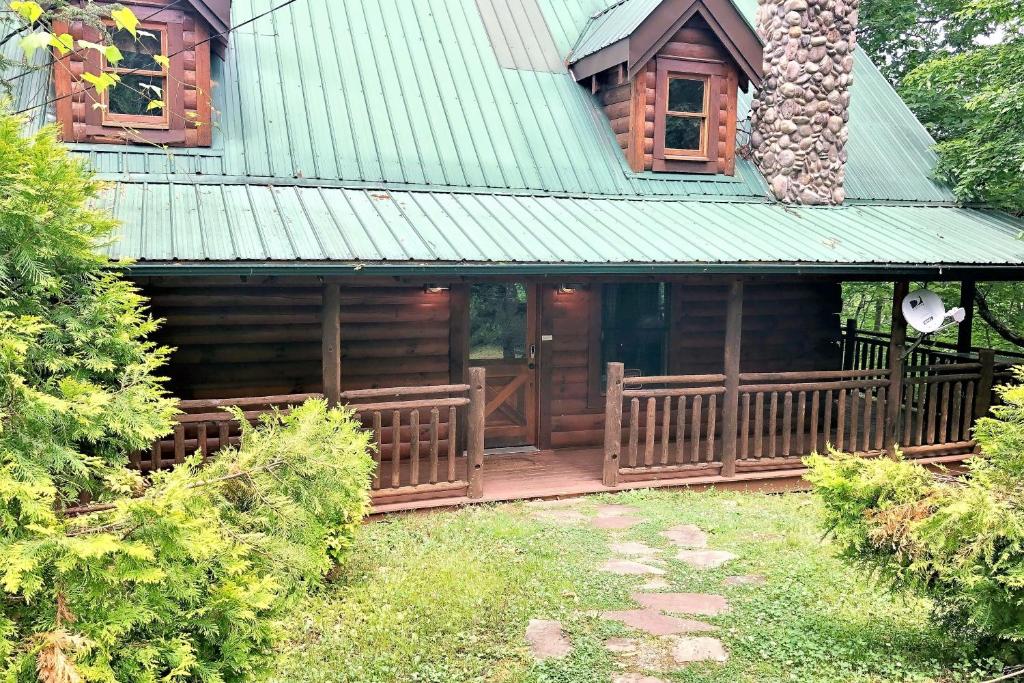 une cabane en rondins avec une véranda et un toit vert dans l'établissement Bear Pleasures, à Gatlinburg