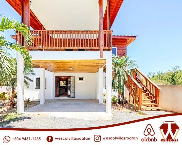 a large house with a staircase and a porch at Wescot Villas Comfort in Roatán