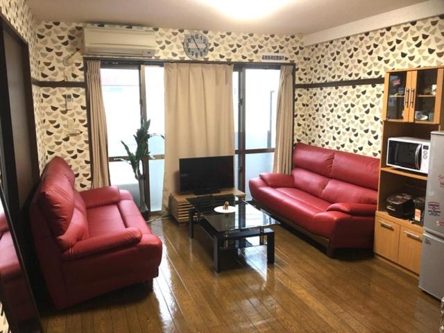 a living room with two red couches and a television at Cozy Family room KY apartment in Naha