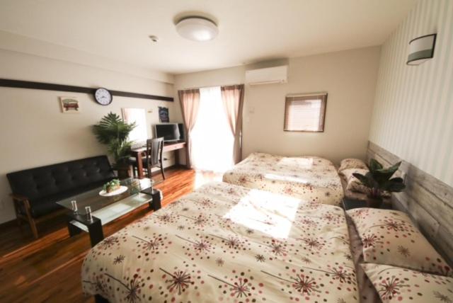 a bedroom with two beds and a living room at Chura Gahna House Tsubogawa Naha in Naha