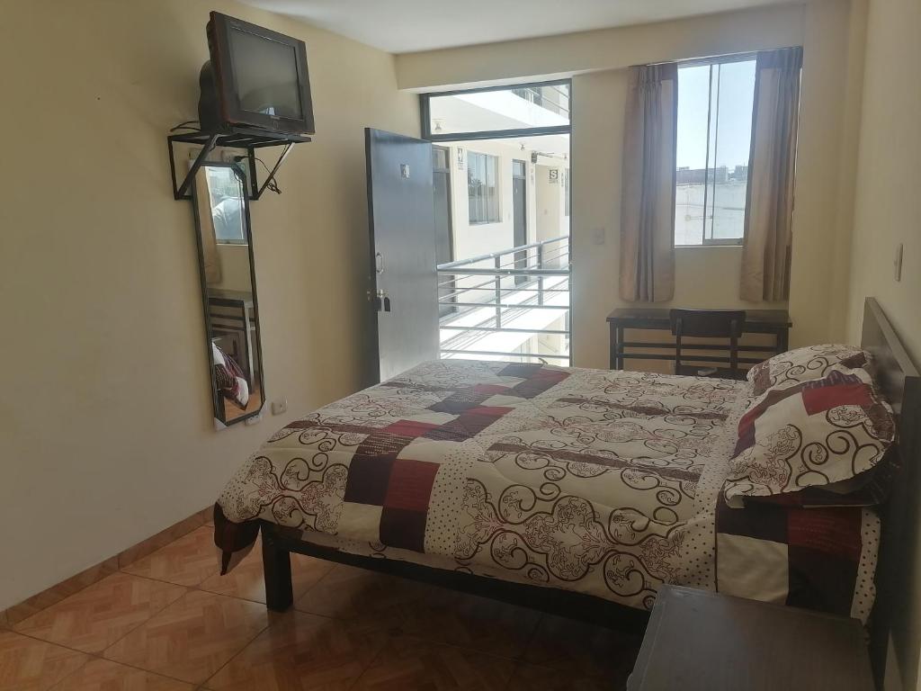 a bedroom with a bed and a tv on the wall at Hostal Carmen in Arequipa