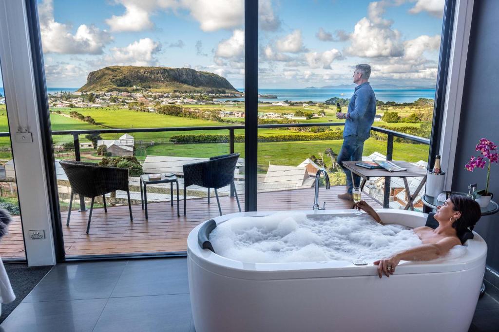 Una mujer en una bañera en una habitación con vistas en Horizon Deluxe Apartments, en Stanley