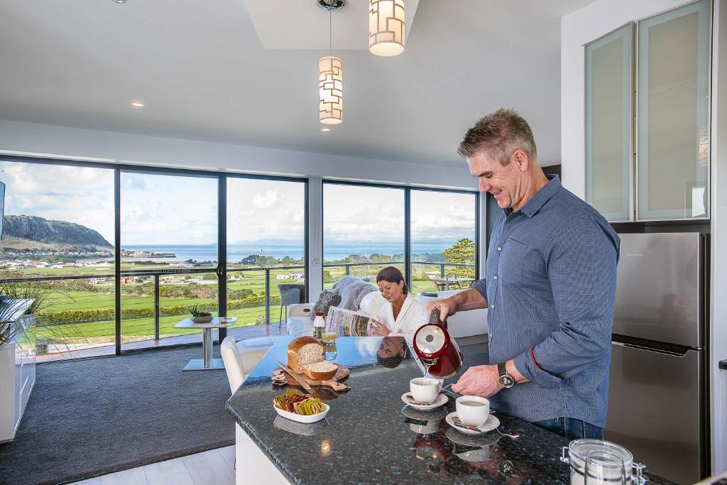 a man and a woman in a kitchen preparing food at Horizon Deluxe Apartments in Stanley