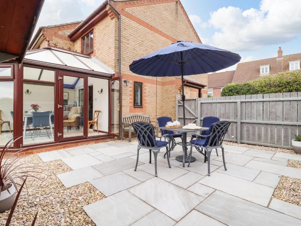 a patio with a table and chairs and an umbrella at 1 Barbers Row in Elmswell