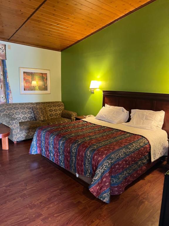 ein Hotelzimmer mit einem Bett und einer grünen Wand in der Unterkunft Town & Country Motel in Clinton