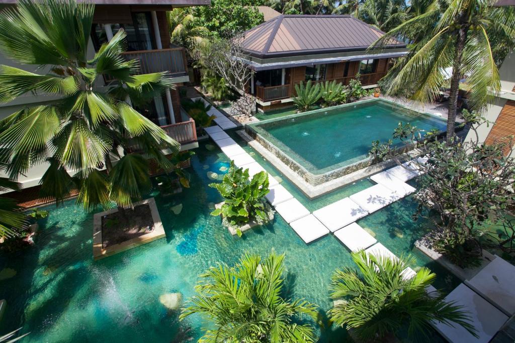 uma vista sobre uma piscina com palmeiras e uma casa em Dhevatara Beach Hotel em Grand'Anse Praslin