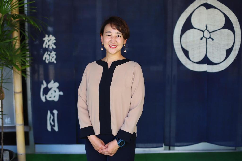 Eine Frau, die vor einer blauen Wand steht. in der Unterkunft Kaigetsu in Toba