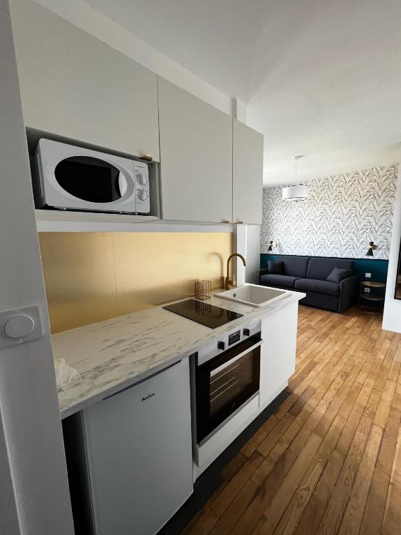 une cuisine avec un micro-ondes et une cuisinière four supérieur dans l'établissement IDÉALEMENT SITUÉ 