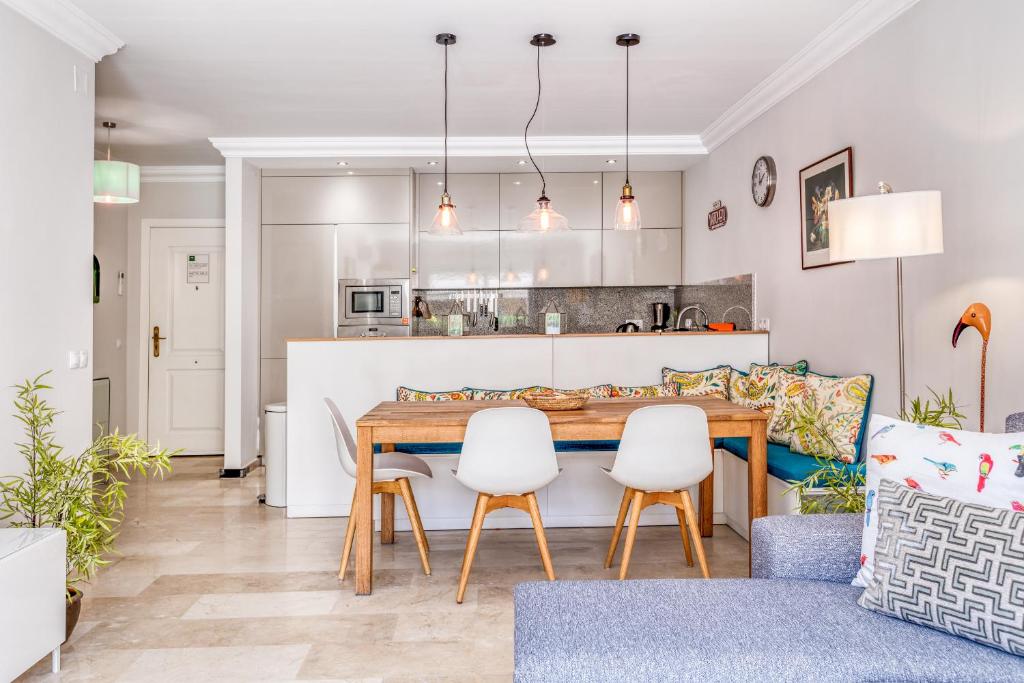 kuchnia i salon z drewnianym stołem i krzesłami w obiekcie Hanami Puerto Alto PA 4-4 w mieście Estepona