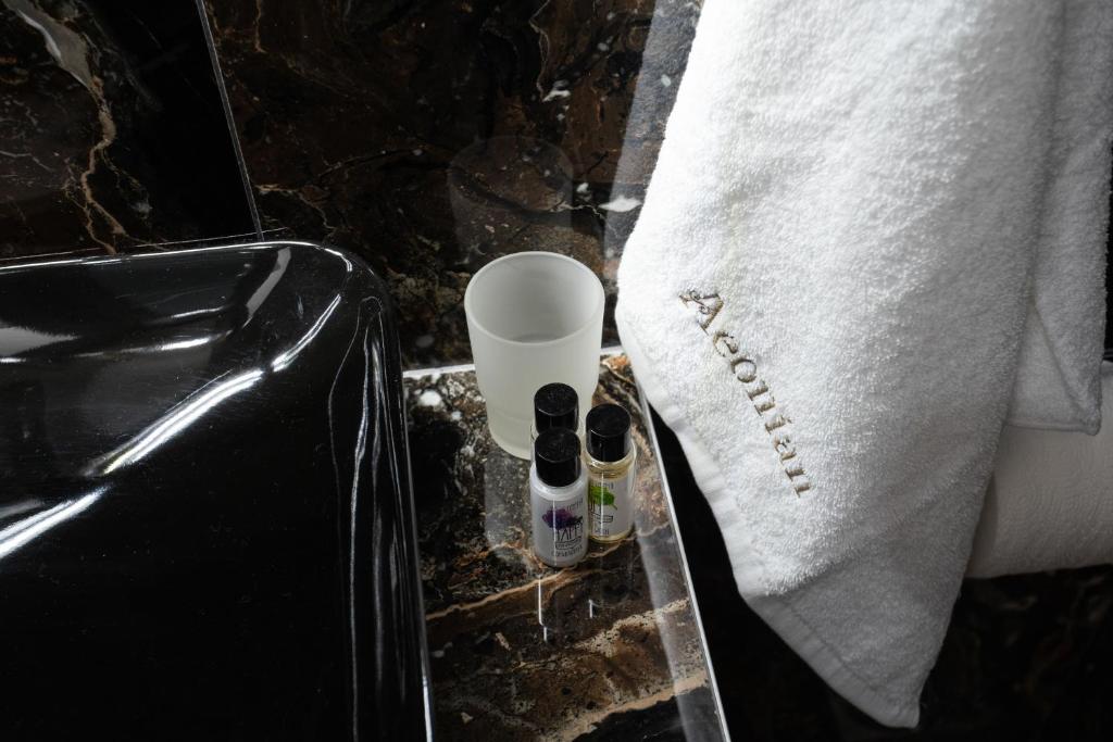 a bathroom counter with a towel and some bottles on it at Aeonian Luxury Suites Asprovalta, Adults Only & Kids 12 Plus in Asprovalta
