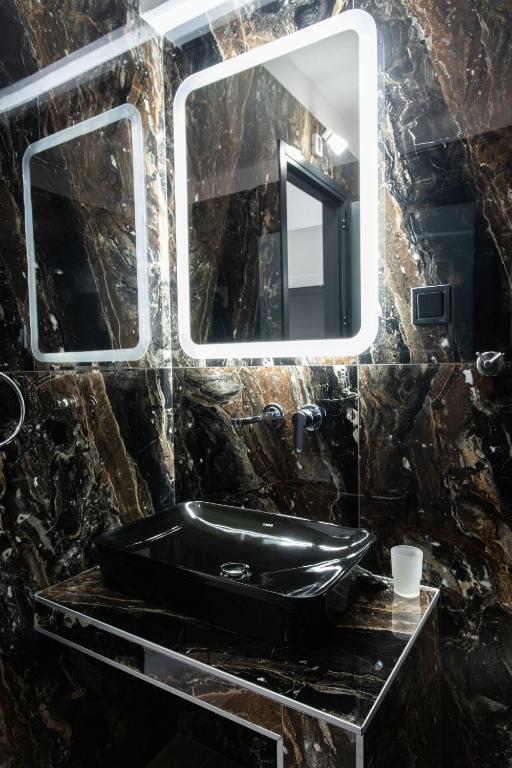 a bathroom with a black sink and a mirror at Aeonian Luxury Suites Asprovalta, Adults Only & Kids 12 Plus in Asprovalta