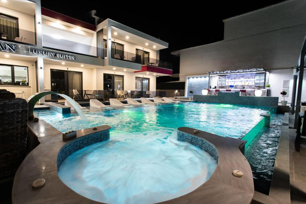 uma grande piscina com uma banheira de hidromassagem num hotel em Aeonian Luxury Suites Asprovalta, Adults Only & Kids 12 Plus em Asprovalta